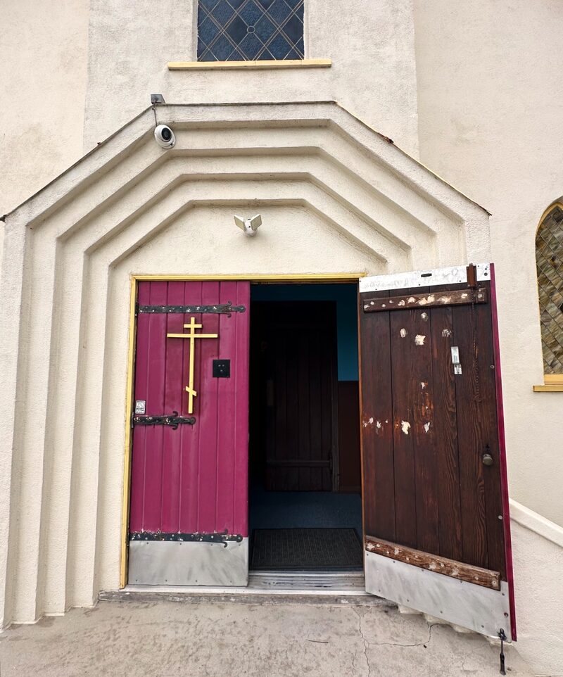 The main entrance doors on Concord Street, with a gold cross on the red door